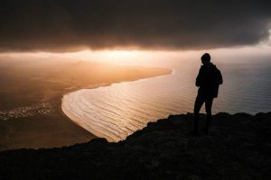 man standing on cliff sunset masonry