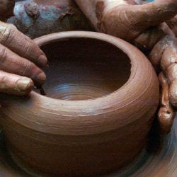 potter forming a clay pot with hands dirty