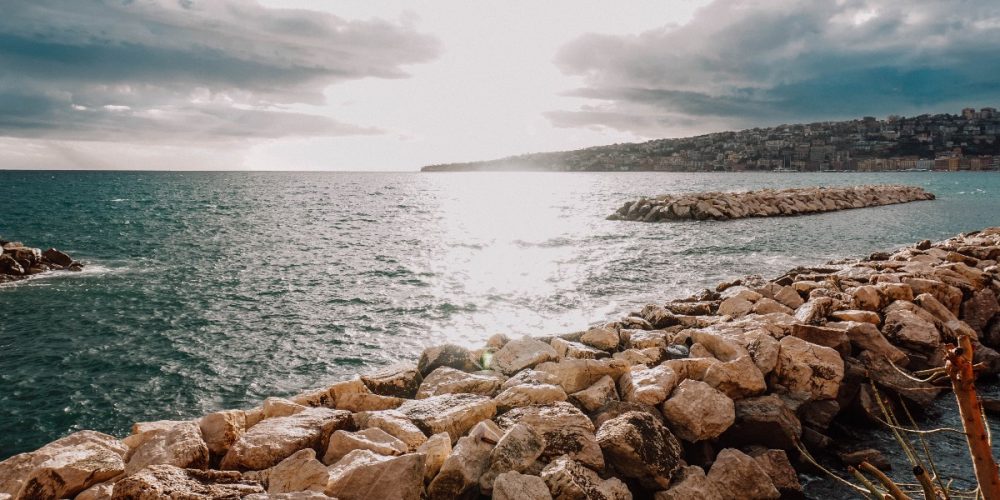 Brown rocks near body of water under white clouds Holland Yeaton scopio