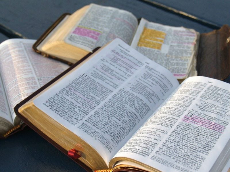 bible study three bibles highlighted on a black park table