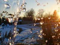 small waterfall with sun shining in winter snow
