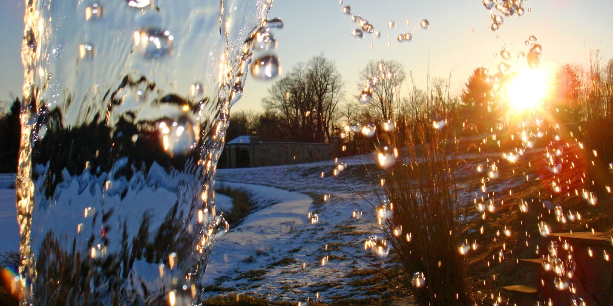 small waterfall with sun shining in winter snow